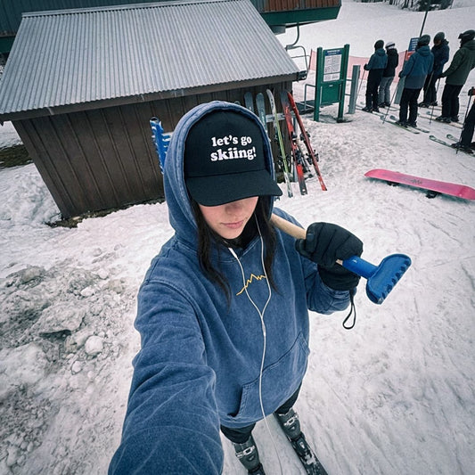 Female skier wearing lets go skiing hat and backcountry veins hoodie.