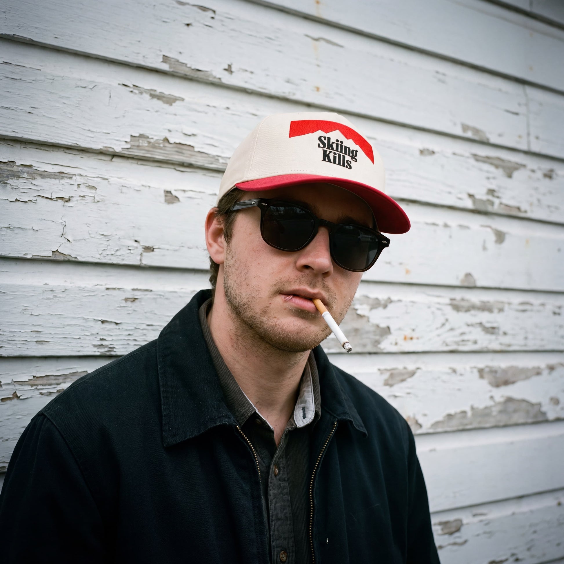 Male model wearing the Skiing Kills hat in Marlboro red and sunglasses.