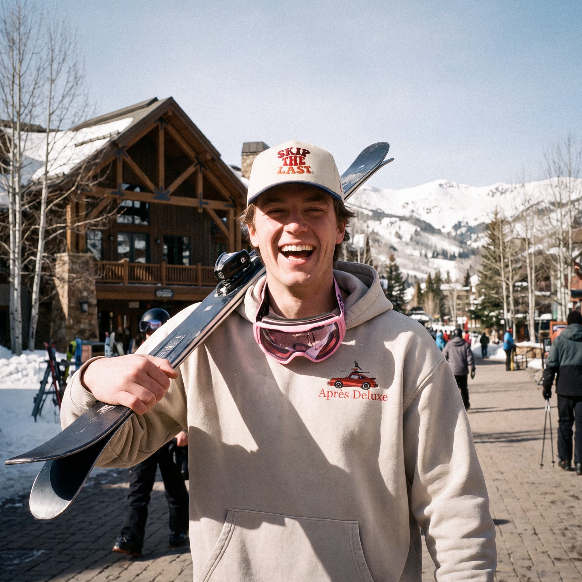 Young man wearing the Skip the Last hat in blue square and the Apres Deluxe hoodie.