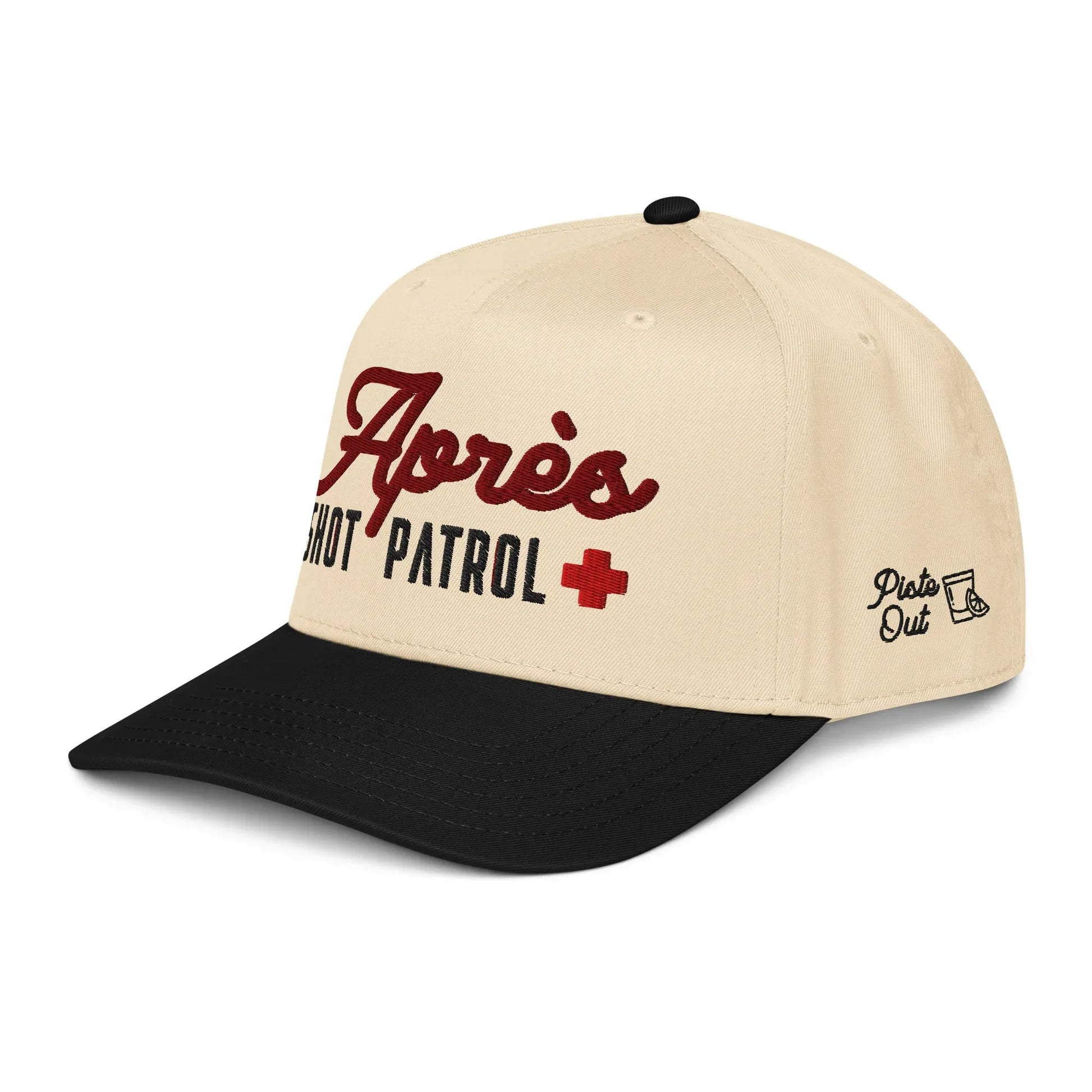 Angled front view of the cream and black Après Shot Patrol hat showing the main embroidery on the front and the side shot-glass icon with the Piste Out logo.