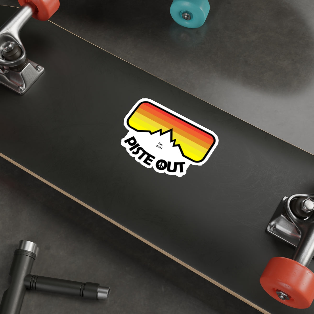 Sticker placed on skateboard deck, featuring vivid goggle design and bold mountain logo