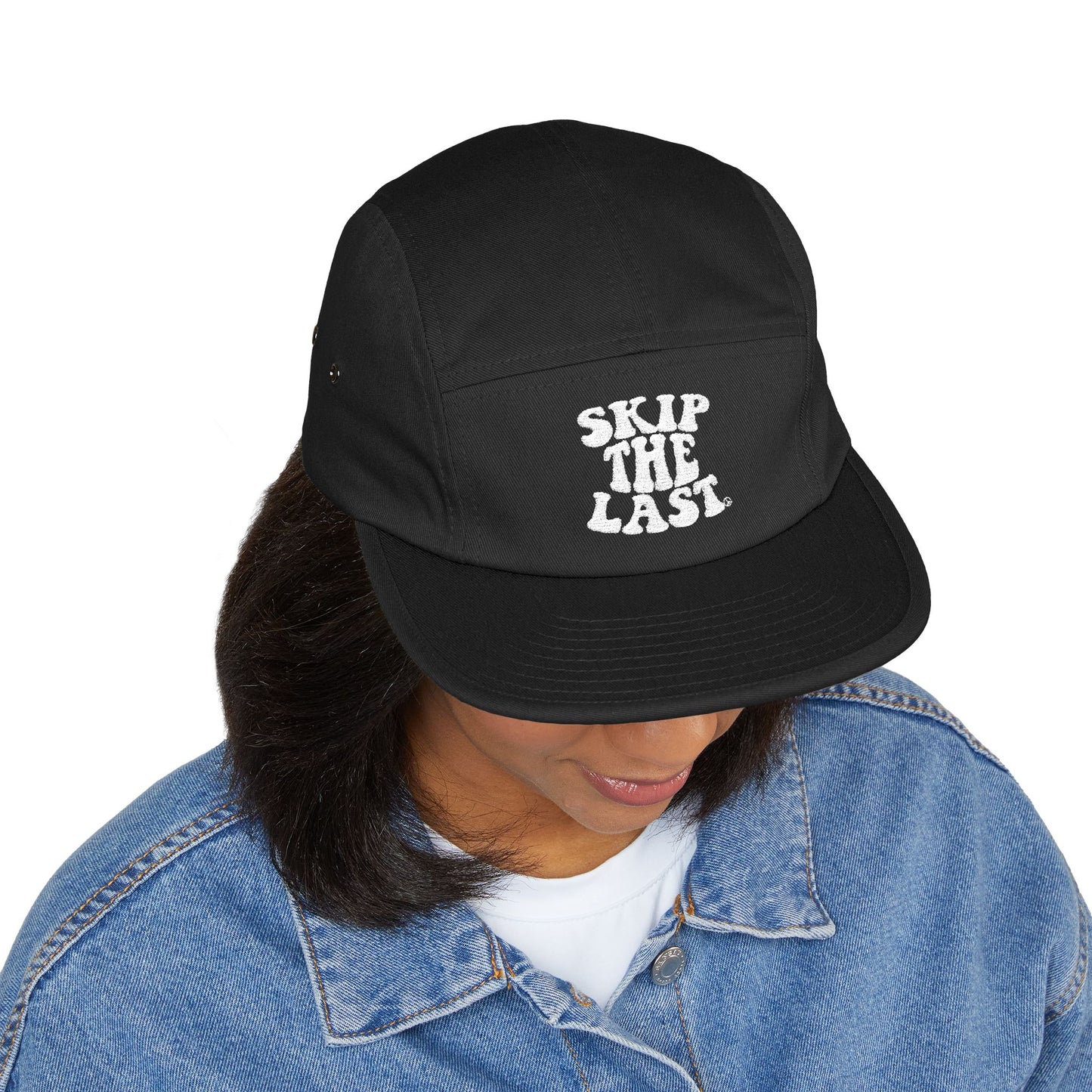 Black Skip the Last 5-panel hat worn by model, front embroidery visible.