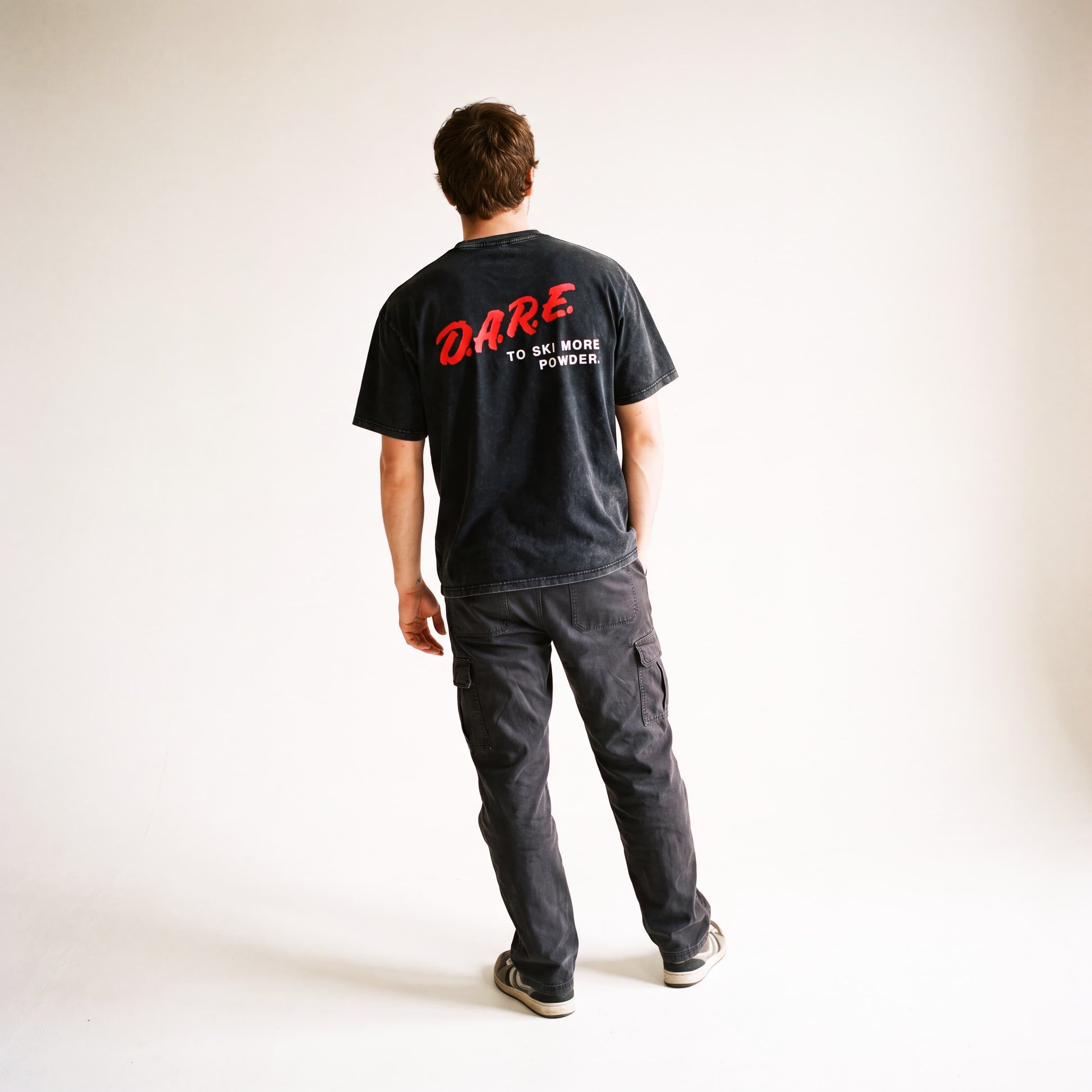 Male model standing and facing away from the camera, wearing the DARE short sleeve tee.