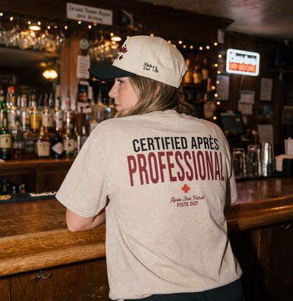 Model wearing apres shot patrol hat and tee in bar. 