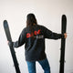 Female model wearing the DARE to Ski More Powder Tee facing away from the camera. 
