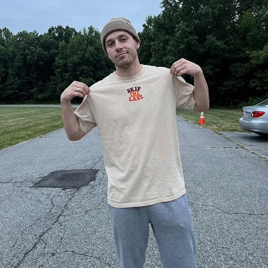 Male model wearing the Skip the last tee in Tan.