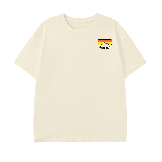 Front view of the Piste Out Logo Tee in cream, showing the signature logo design on a light brown cotton shirt. Casual unisex fit, short sleeves, round neck.