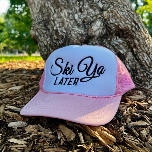 Pink variant of the ski ya later trucker hat outdoors.