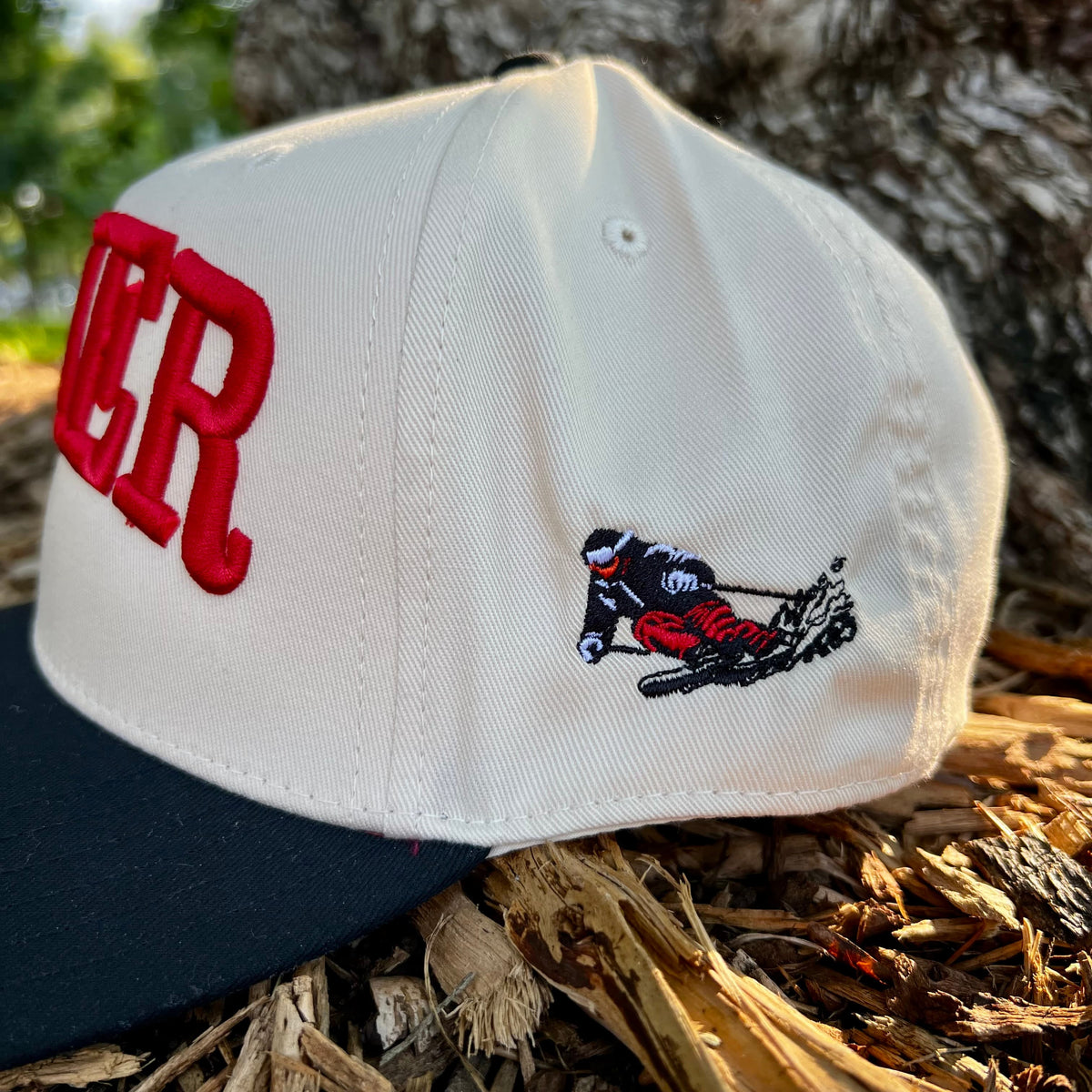 Skier Cap in Blue Square, angled front view showing vintage downhill skier side panel graphic close up, outdoors