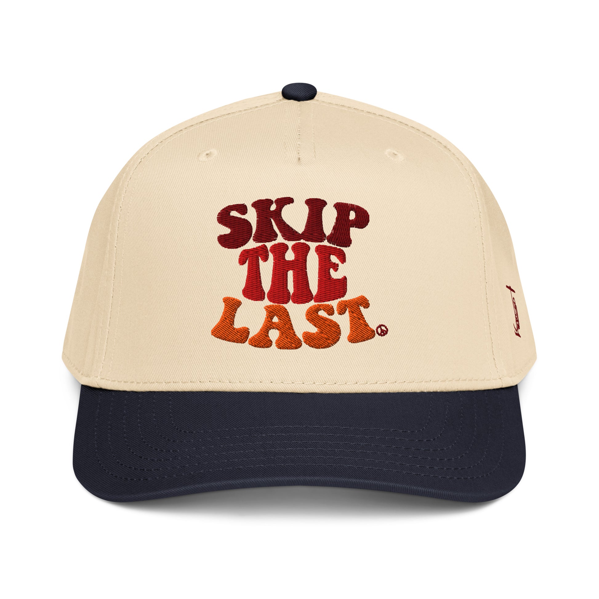 Front view of the Skip the Last two-tone ski superstition hat in Blue Square, featuring a cream crown, blue brim, maroon-orange gradient embroidery, and side skier lift graphic.