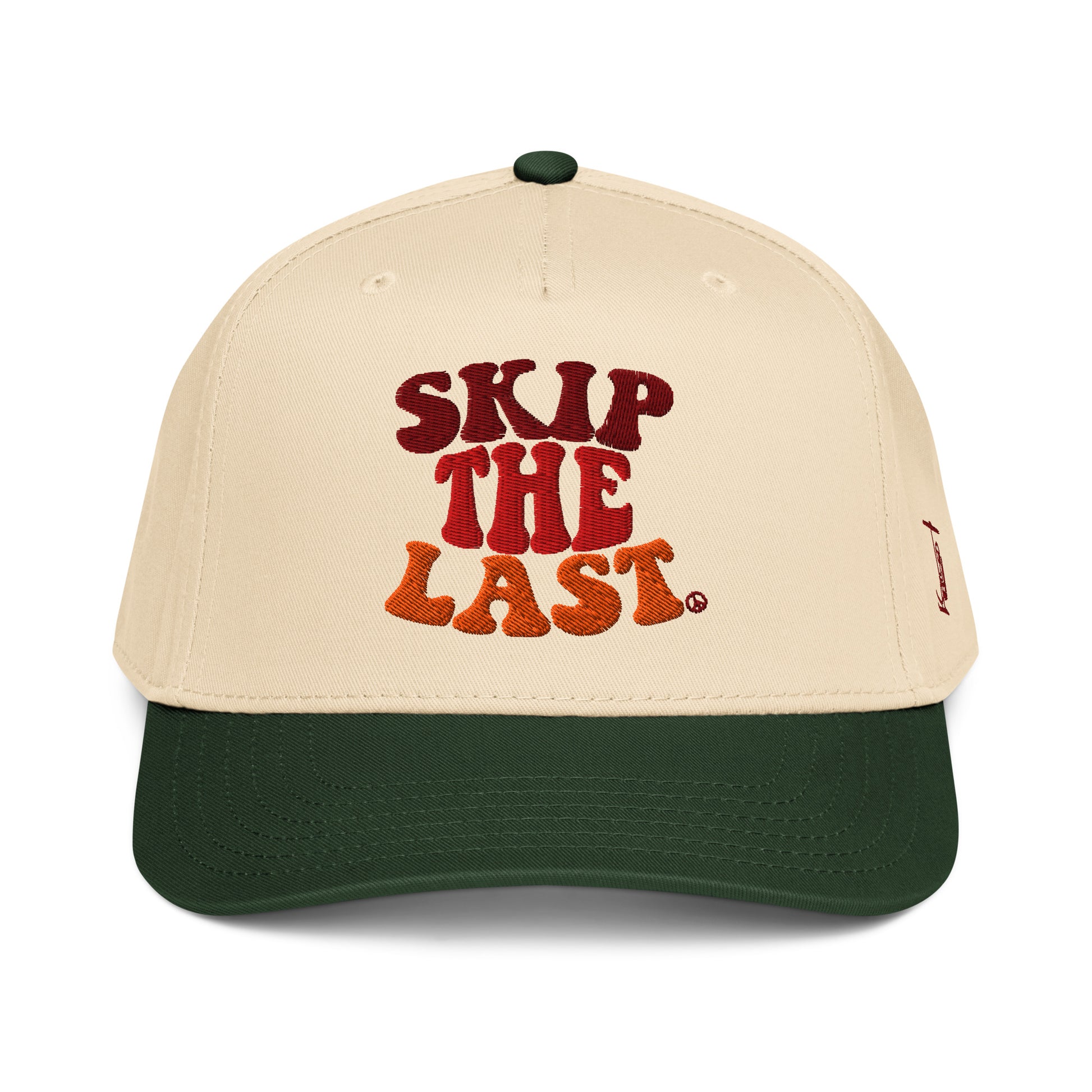 Front view of the Skip the Last two-tone ski superstition hat in Green Circle, featuring a cream crown, green brim, maroon-orange gradient embroidery, and side skier lift design.