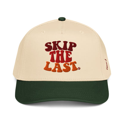Front view of the Skip the Last two-tone ski superstition hat in Green Circle, featuring a cream crown, forest green brim, maroon-orange gradient embroidery, and side skier lift design.