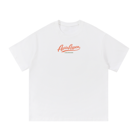 Snow white Après Aspen ski tee front view with coral Après Aspen logo and green Colorado text.