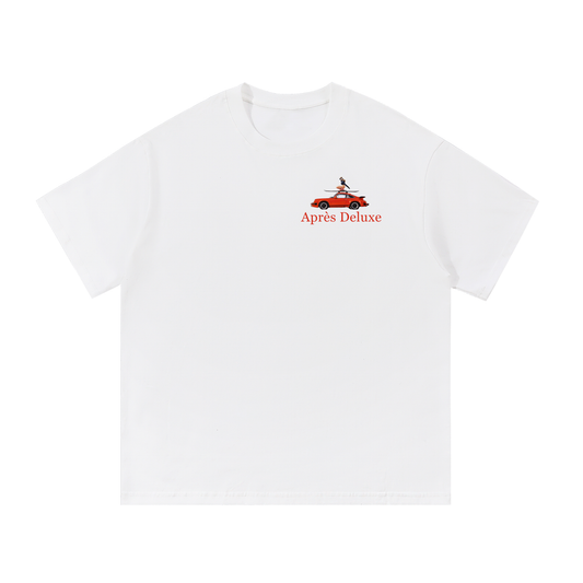 Snow Après Deluxe tee front view with small left-chest red “Après Deluxe” text and mini red car graphic with skier on skis.