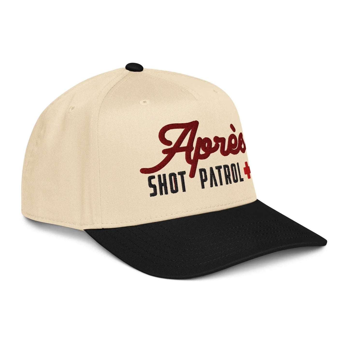 Side angle view of the Après Shot Patrol hat in cream and black, displaying the front embroidery and the side Piste Out script with a shot-glass icon.
