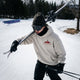 Park skier wearing the apres deluze hoodie in Snow carrying skis on his shoulder