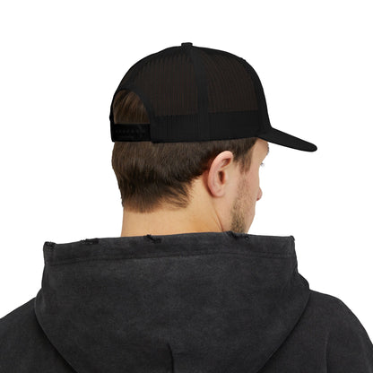 Rear angle of black trucker hat worn by model, showing mesh back and snapback closure