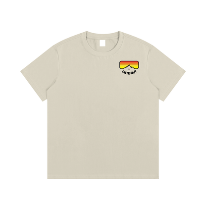 Front view of khaki Piste Out logo tee with small left-chest retro goggle logo in red, orange and yellow gradient.