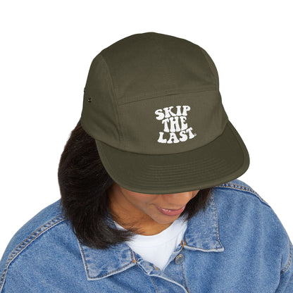 Olive green Skip the Last 5-panel hat worn by model, front embroidery visible.